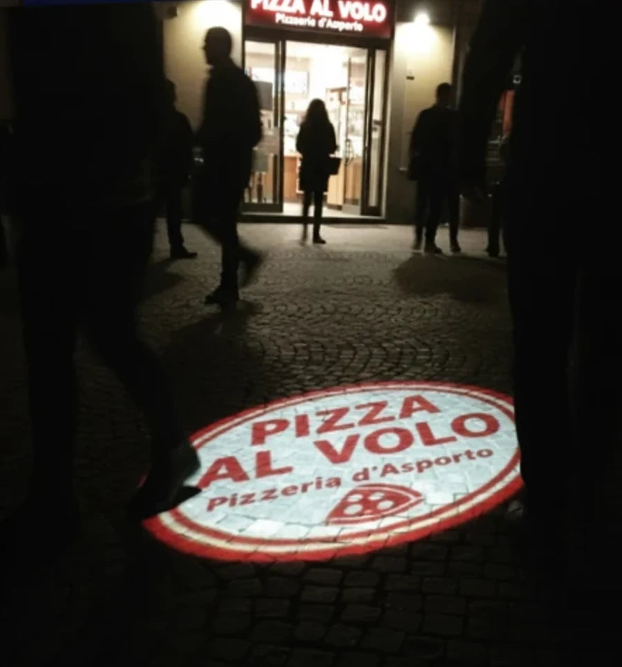 Logo della pizzeria proiettato sul selciato davanti all'ingresso